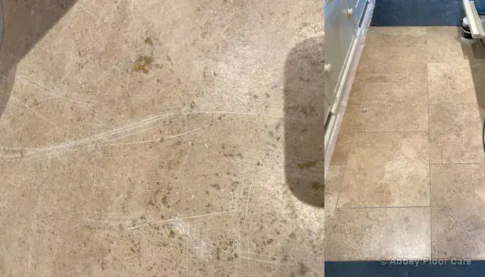Before restoration: Worn travertine kitchen and dining room floor showing dull traffic lanes, dark soiled grout lines, light scratches, and open holes with missing filler